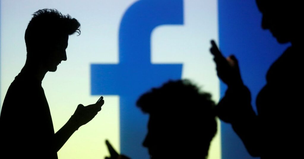 People are silhouetted as they pose with mobile devices in front of a screen projected with a Facebook logo, in this picture illustration taken in Zenica October 29, 2014. REUTERS/Dado Ruvic