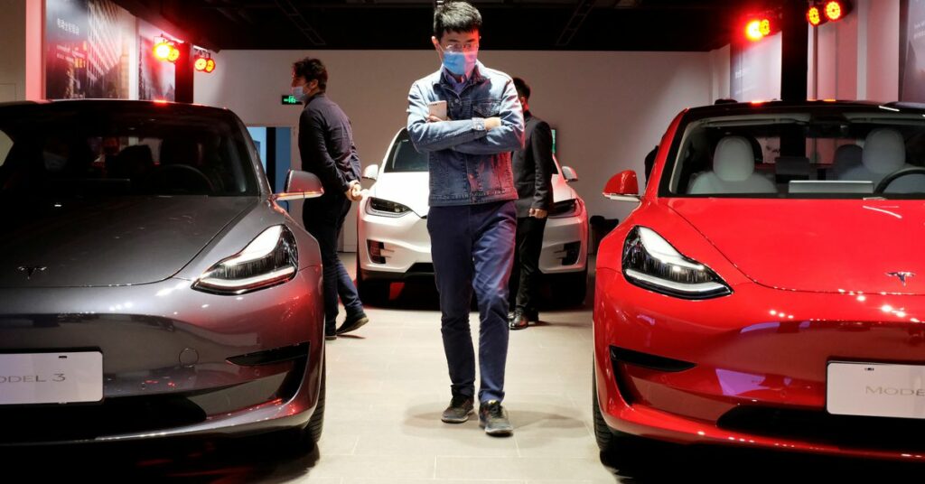 A man wearing a face mask following the coronavirus disease (COVID-19) outbreak walks by Tesla Model 3 sedans and Tesla Model X sport utility vehicle at a new Tesla showroom in Shanghai, China May 8, 2020. REUTERS/Yilei Sun