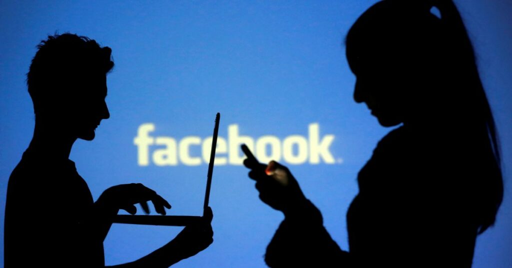 People are silhouetted as they pose with laptops in front of a screen projected with a Facebook logo, in this picture illustration taken in Zenica, October 29, 2014. REUTERS/Dado Ruvic