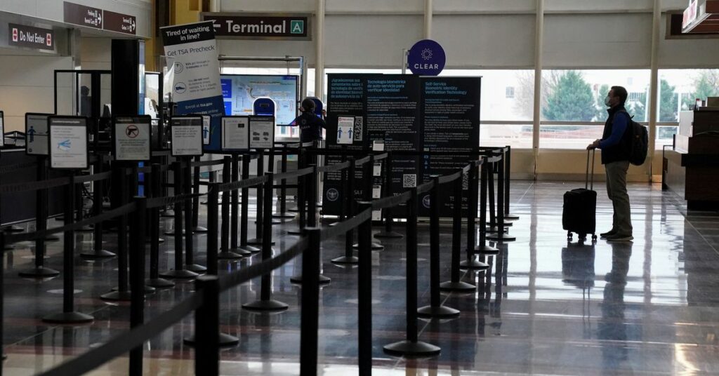 A Christmas week traveler stands by a security gate at Ronald Reagan Washington National Airport, in Arlington, Virginia, U.S., December 22, 2020.  REUTERS/Kevin Lamarque