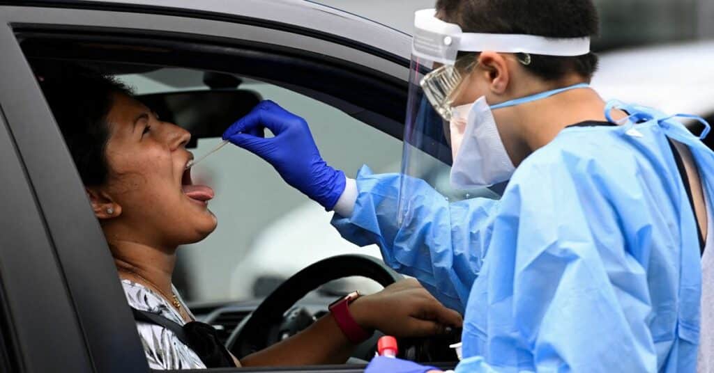 A woman in line at a coronavirus (COVID-19) testing centre steps out of her vehicle to look at the queue of traffic blocking a Western Sydney highway in Sydney, Australia, January 5, 2022.  REUTERS/Jaimi Joy