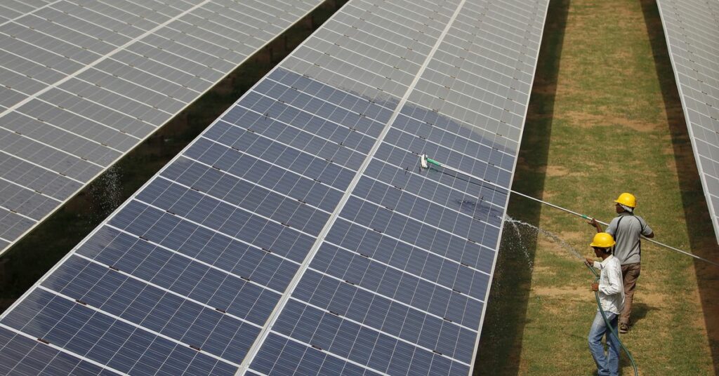 Workers clean photovoltaic panels inside a solar power plant in Gujarat, India, July 2, 2015. REUTERS/Amit Dave