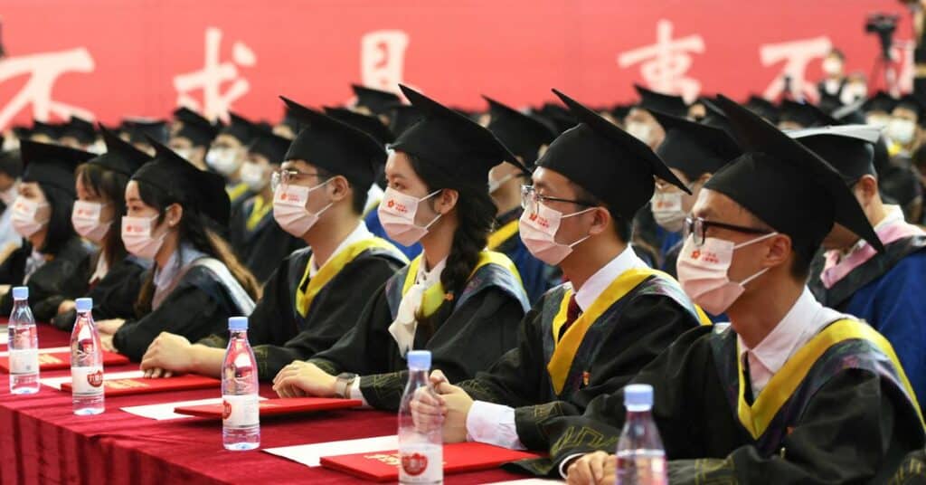 Students take graduation photo in front of the statue of Chinese leader Mao Zedong and a signboard marking the 100th founding anniversary of the Communist Party of China, at Fudan University in Shanghai