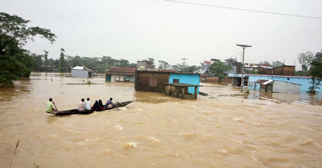 People move a boat in a flooded area during a widespread flood in Sylhet