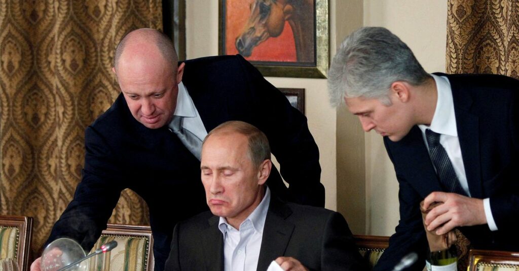 Yevgeny Prigozhin assists Russian Prime Minister Vladimir Putin during a dinner with foreign scholars and journalists at the restaurant Cheval Blanc on the premises of an equestrian complex outside Moscow