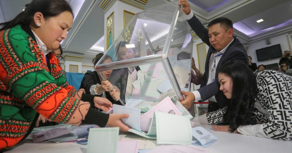 Members of a local election committee empty a ballot box to count votes after polls closed during parliamentary election in Almaty