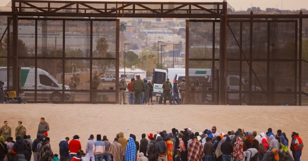 Migrants stand near the border wall after crossing the Rio Bravo river, as seen from Ciudad Juarez