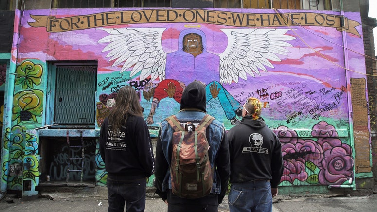 Ronnie Grigg, Trey Helton y Shawn Hefele mirando un mural conmemorativo que crearon en el callejón detrás de OPS