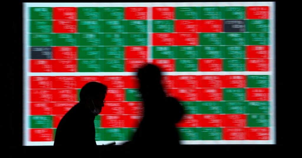 Passersby walk past an electric stock quotation board outside a brokerage in Tokyo