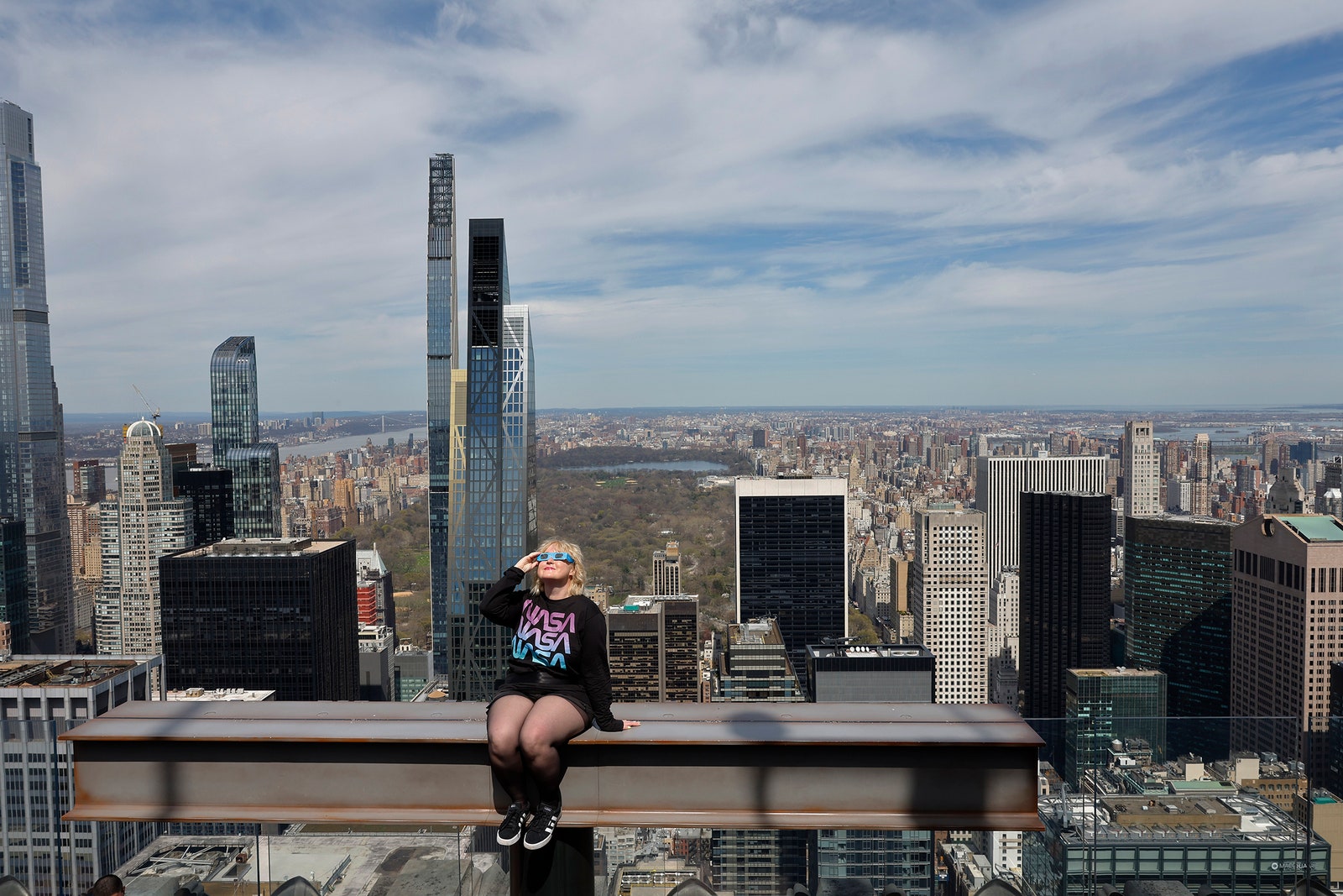 Foto de una mujer con gafas de eclipse en el Haz mientras se prepara para observar un eclipse solar parcial desde la cima del...