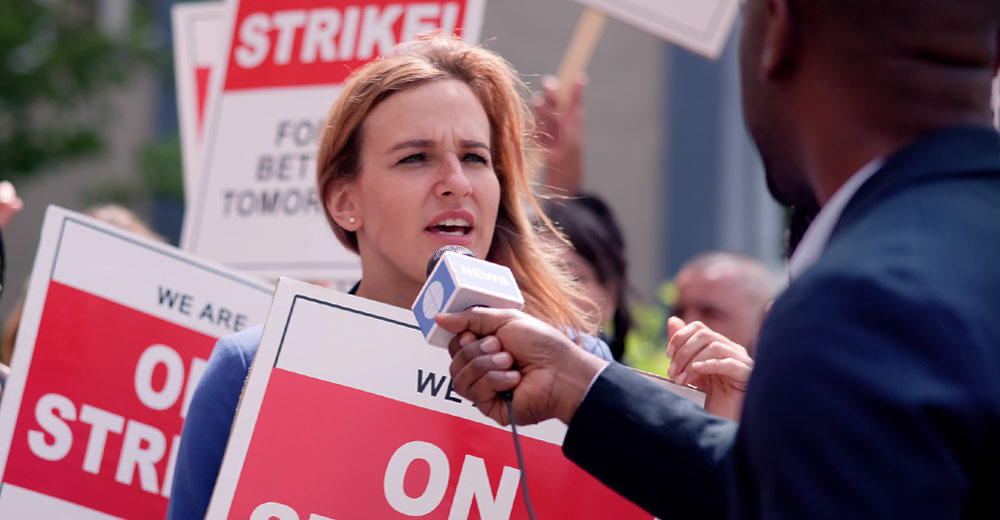 union workers on strike interviewed by news reporter